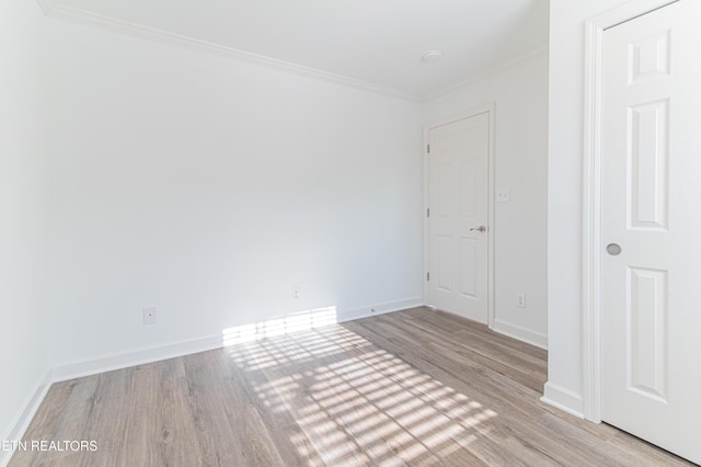 empty room with light wood-type flooring and crown molding