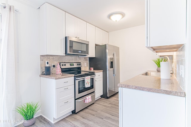 kitchen with tasteful backsplash, white cabinetry, and appliances with stainless steel finishes