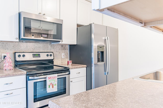 kitchen with decorative backsplash, white cabinetry, and appliances with stainless steel finishes