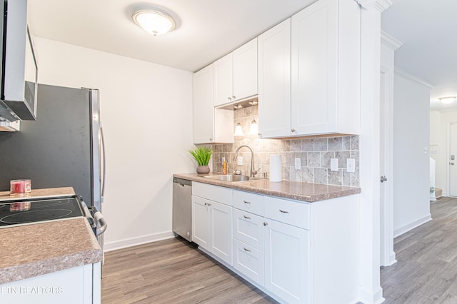 kitchen featuring appliances with stainless steel finishes, backsplash, sink, light hardwood / wood-style floors, and white cabinetry