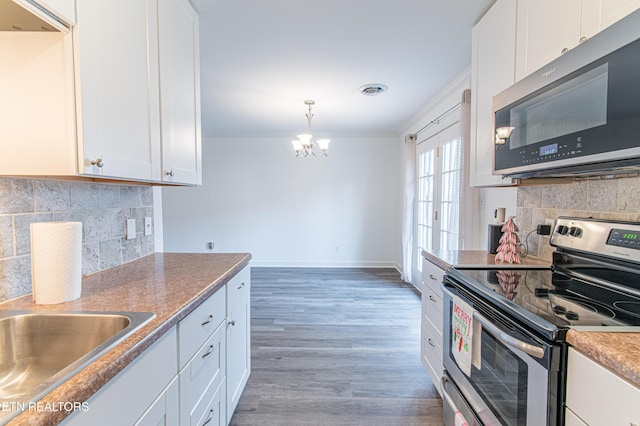 kitchen with crown molding, an inviting chandelier, white cabinets, and appliances with stainless steel finishes