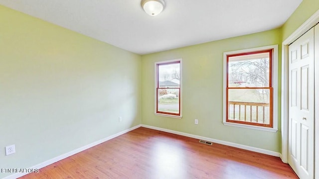 unfurnished bedroom featuring hardwood / wood-style flooring, multiple windows, and a closet