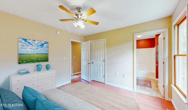 bedroom with connected bathroom, ceiling fan, and light wood-type flooring