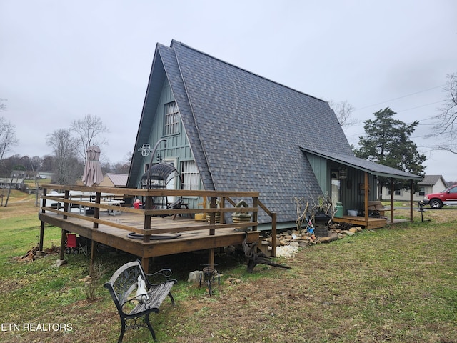 back of property featuring a wooden deck and a lawn