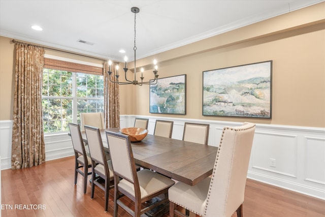 dining room featuring crown molding, wood-type flooring, and a chandelier