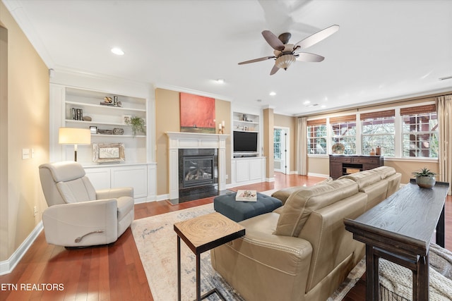 living room with wood-type flooring, ceiling fan, crown molding, and built in shelves