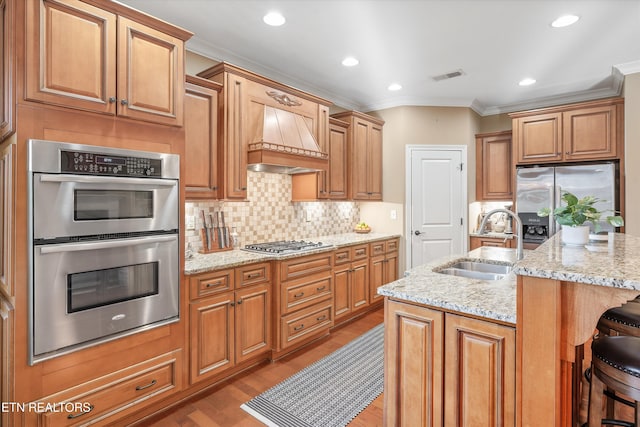 kitchen with custom exhaust hood, an island with sink, sink, and a breakfast bar area