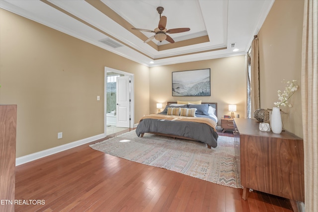 bedroom featuring ceiling fan, hardwood / wood-style floors, connected bathroom, ornamental molding, and a raised ceiling