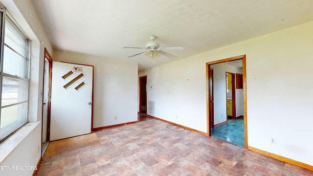 empty room featuring ceiling fan and a wealth of natural light