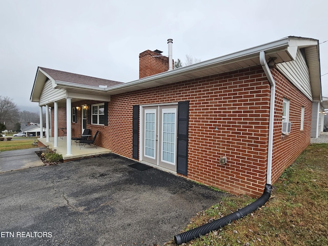 view of side of home featuring french doors, cooling unit, and a porch