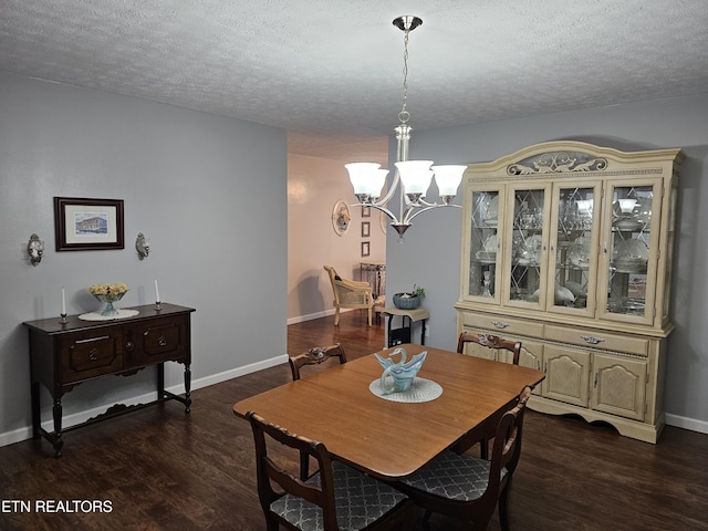 dining space featuring a textured ceiling, dark wood-type flooring, and a notable chandelier