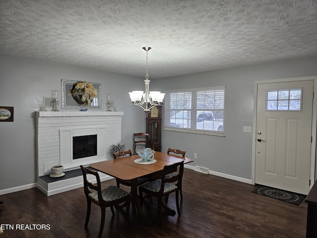 dining room with a textured ceiling, dark hardwood / wood-style floors, a brick fireplace, and a wealth of natural light