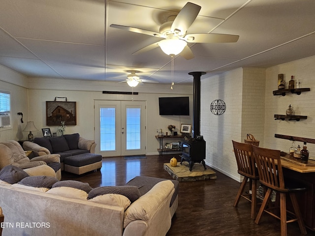 living room with dark hardwood / wood-style flooring, a wood stove, a healthy amount of sunlight, and brick wall