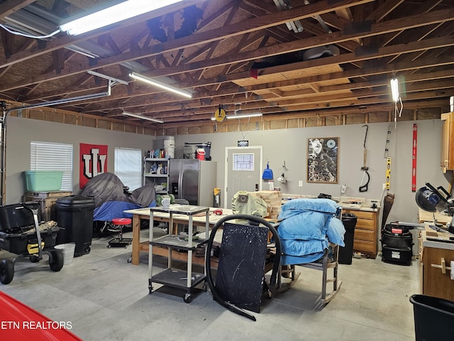 garage featuring a workshop area and stainless steel fridge with ice dispenser