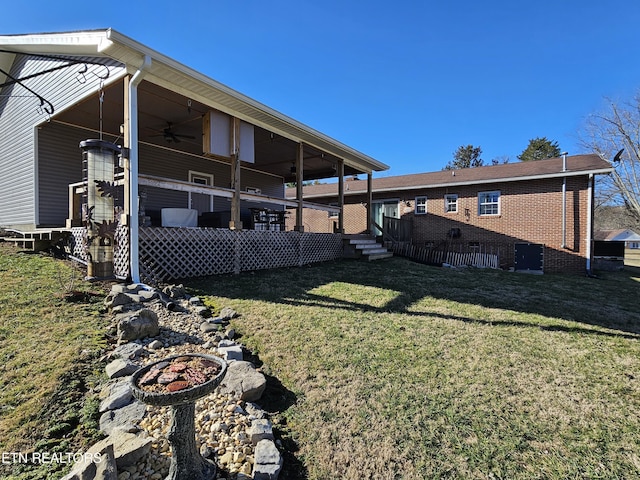 back of property with ceiling fan, a yard, and brick siding