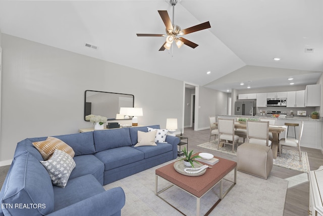 living room featuring ceiling fan, light hardwood / wood-style floors, and lofted ceiling