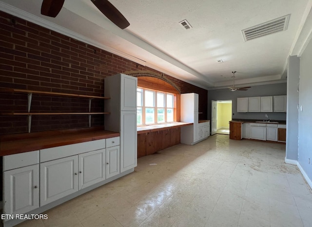 interior space featuring white cabinetry, ceiling fan, crown molding, and built in desk