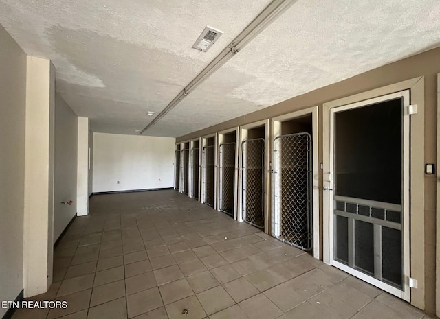 hall featuring tile patterned floors and a textured ceiling