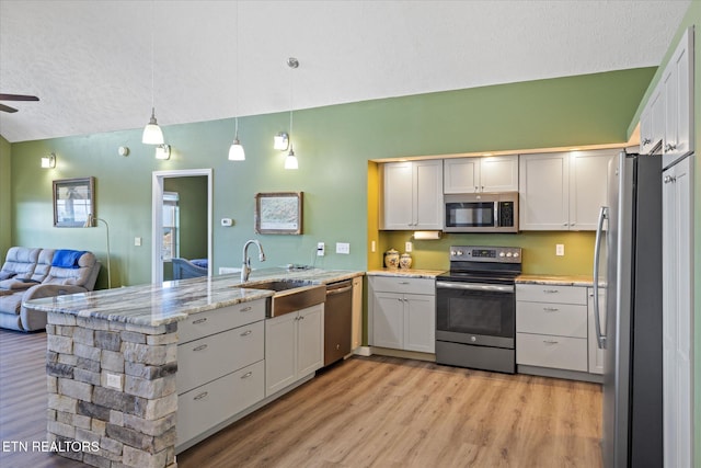 kitchen with white cabinets, sink, hanging light fixtures, appliances with stainless steel finishes, and kitchen peninsula