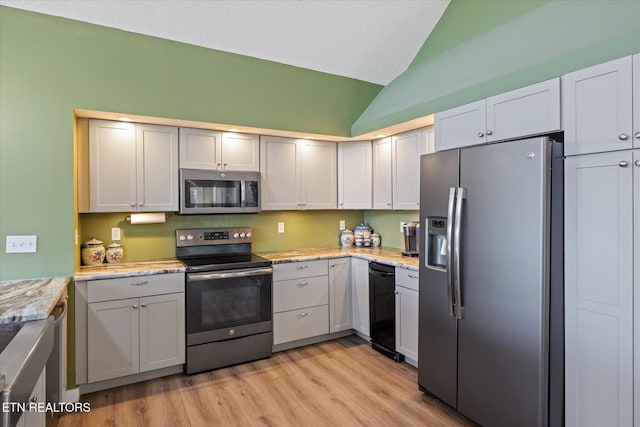 kitchen with light wood-type flooring, light stone counters, stainless steel appliances, gray cabinets, and lofted ceiling