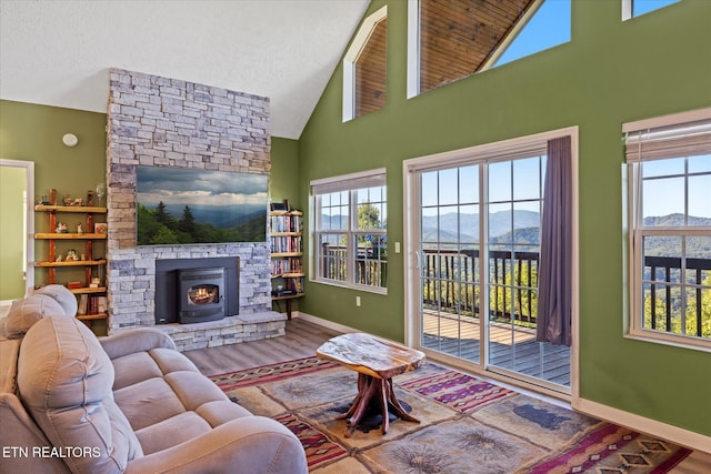 living room with a wood stove, a wealth of natural light, wood-type flooring, and vaulted ceiling