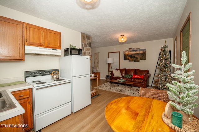 kitchen featuring light hardwood / wood-style floors, white appliances, and a textured ceiling