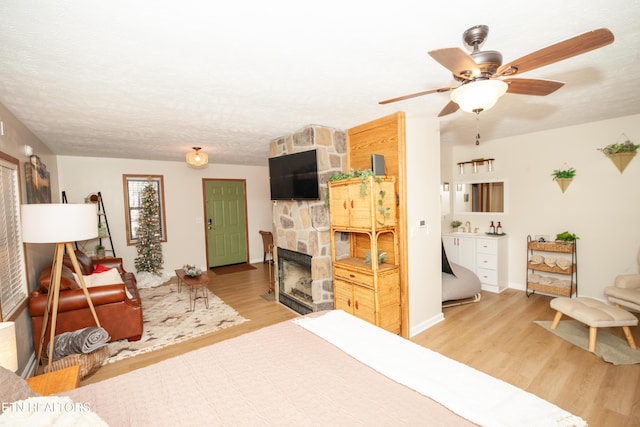 bedroom with a fireplace, a textured ceiling, and light wood-type flooring