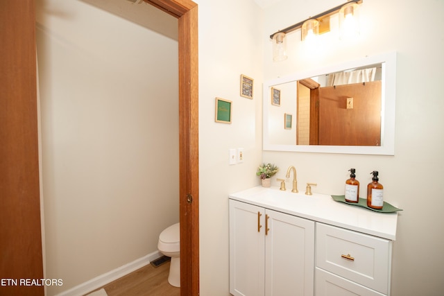 bathroom featuring wood-type flooring, toilet, and vanity