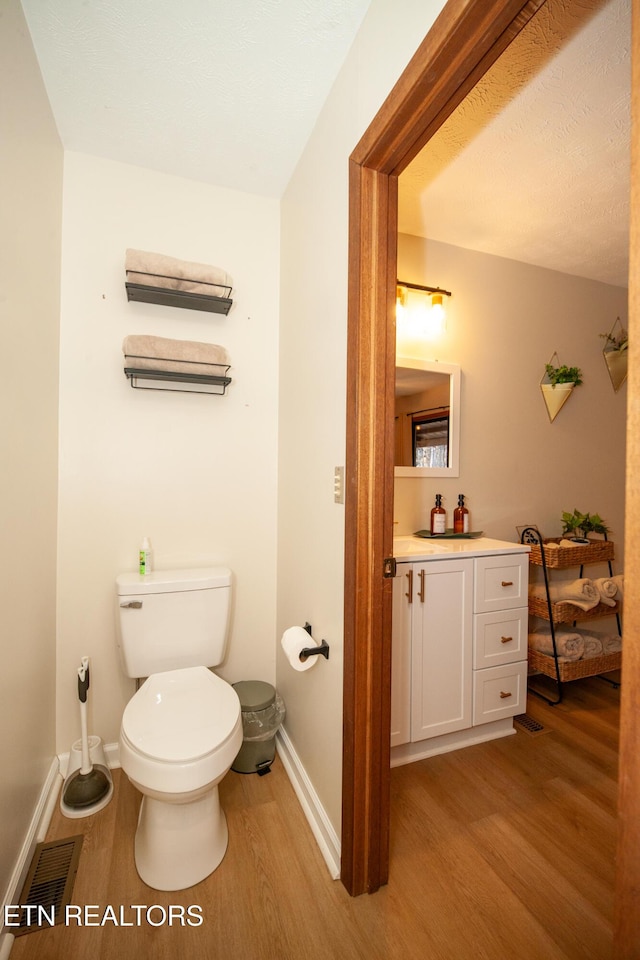 bathroom with toilet, hardwood / wood-style flooring, and vanity