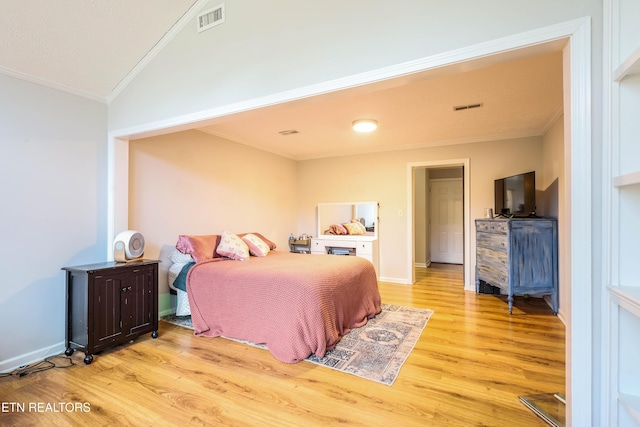 bedroom with light wood-type flooring, vaulted ceiling, and crown molding