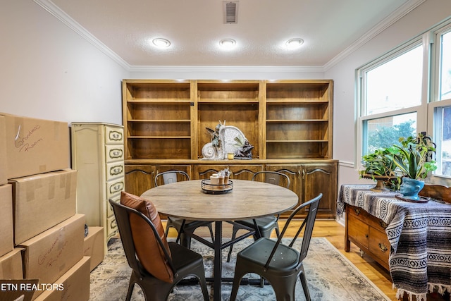 dining space with light hardwood / wood-style floors and ornamental molding