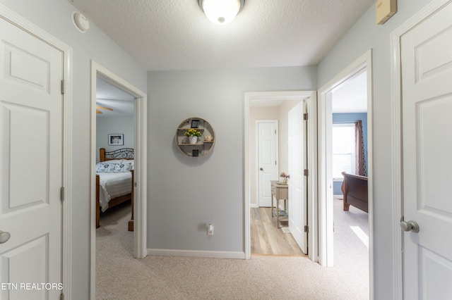 hall with light carpet and a textured ceiling