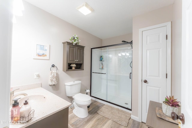 bathroom with hardwood / wood-style floors, vanity, toilet, and a shower with door