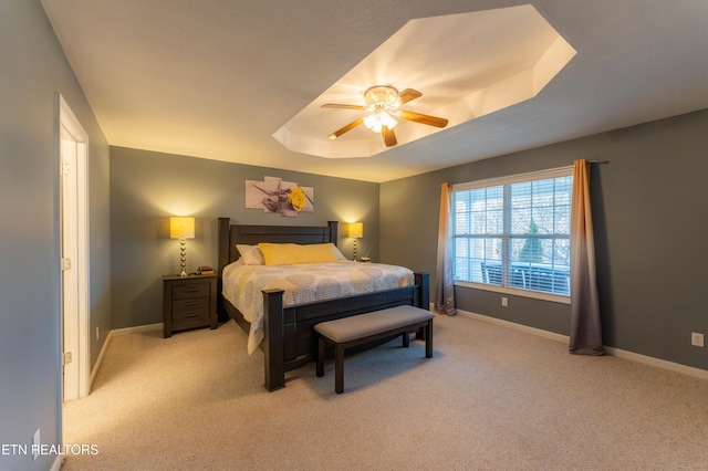 carpeted bedroom with a raised ceiling and ceiling fan