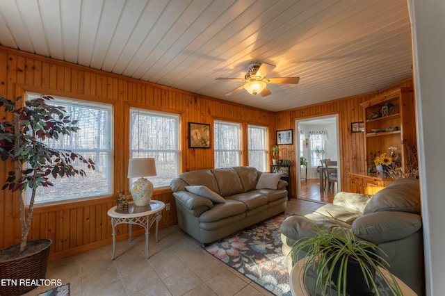 living room featuring ceiling fan, wood walls, and light tile patterned floors