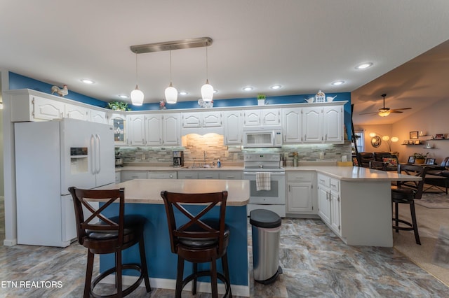 kitchen with a kitchen bar, white appliances, ceiling fan, a center island, and white cabinetry