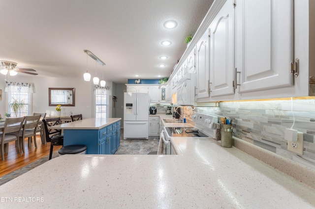 kitchen with pendant lighting, white appliances, backsplash, white cabinets, and blue cabinetry