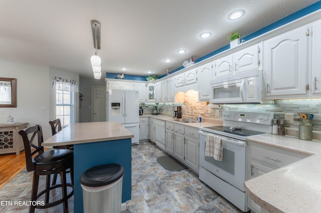 kitchen featuring white cabinetry, a kitchen island, decorative light fixtures, and white appliances