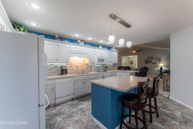 kitchen with white appliances, ceiling fan, sink, white cabinets, and a kitchen island