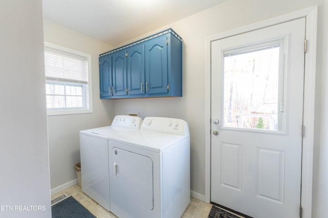 clothes washing area featuring a healthy amount of sunlight, cabinets, light tile patterned flooring, and washing machine and clothes dryer