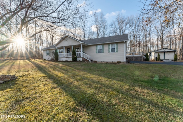 ranch-style home with a front yard, a porch, an outbuilding, and a garage