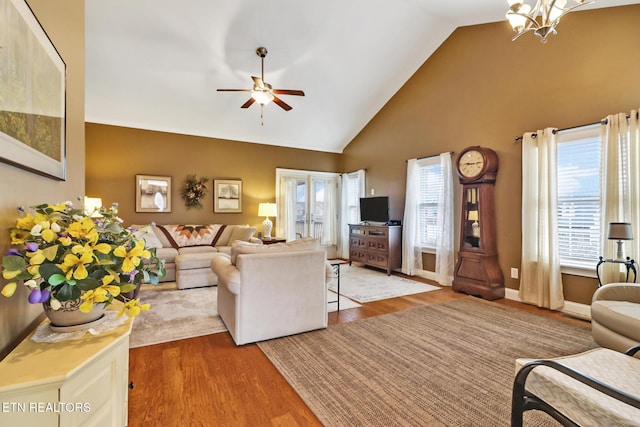 living room featuring hardwood / wood-style floors, ceiling fan with notable chandelier, and high vaulted ceiling