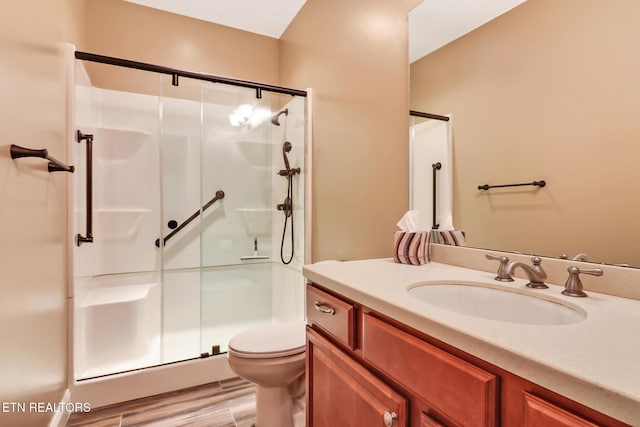 bathroom featuring hardwood / wood-style floors, vanity, toilet, and a shower with shower door