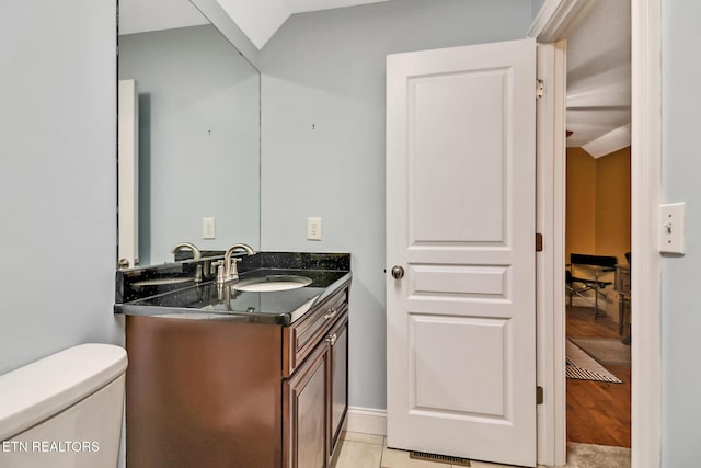 bathroom with tile patterned flooring, vanity, lofted ceiling, and toilet