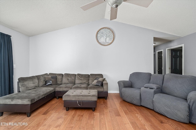 living room with ceiling fan, vaulted ceiling, hardwood / wood-style floors, and a textured ceiling