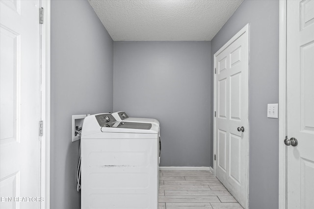 laundry area with a textured ceiling, washer and dryer, and light wood-type flooring