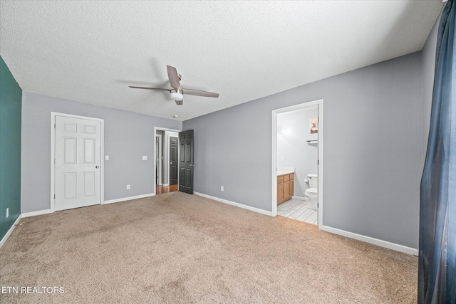 unfurnished bedroom featuring ceiling fan, light colored carpet, connected bathroom, and a textured ceiling