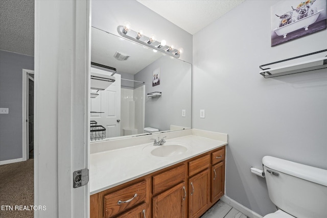 bathroom with vanity, a textured ceiling, toilet, and walk in shower