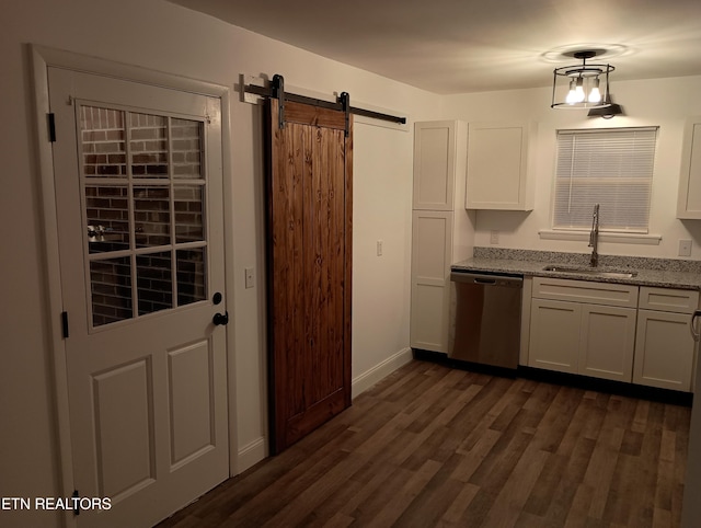 kitchen featuring light stone countertops, stainless steel dishwasher, sink, a barn door, and white cabinets