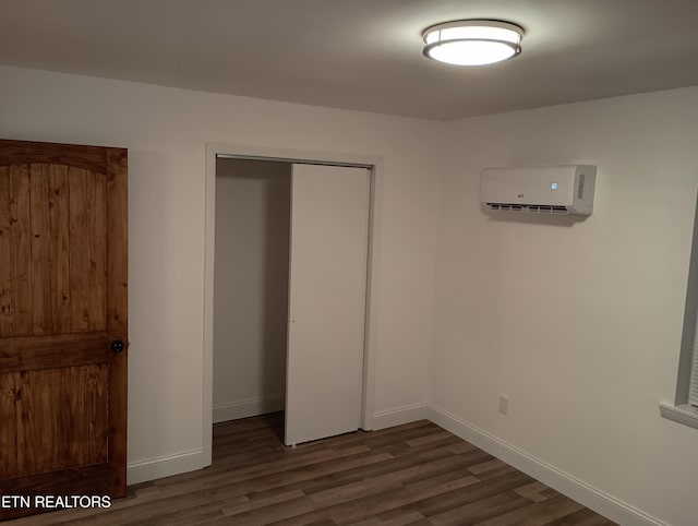 unfurnished bedroom featuring a closet, a wall mounted AC, and dark wood-type flooring